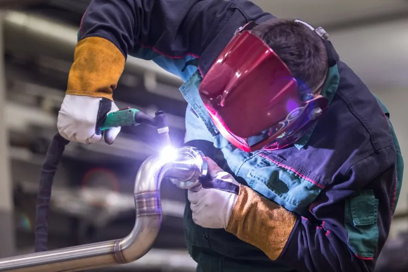 Welder joining a steel pipe bend